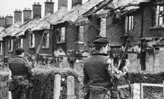 Image of British soldiers stand on guard over houses in Belfast during the Troubles